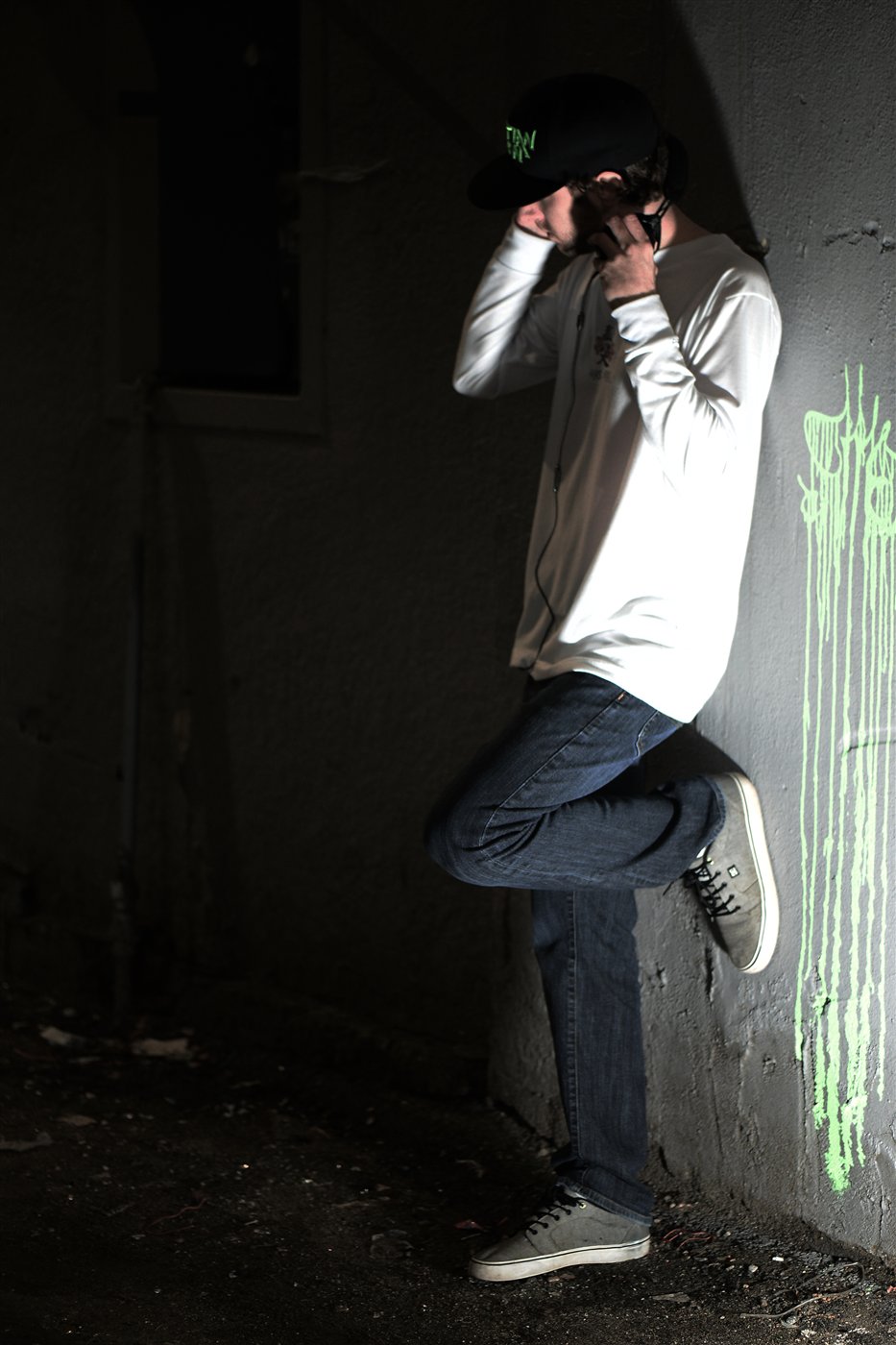 Martian Moon wearing headphones, photographed beside a wall